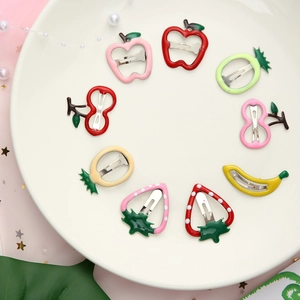 Set of colorful fruit-shaped hair clips for kids on white plate with pink tulle décor