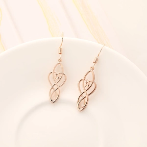 Detail view of rose gold celtic knot earrings hanging on a white ceramic display plate
