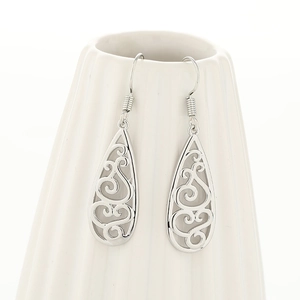 Detailed close-up of silver teardrop earrings with intricate hollow celtic patterns