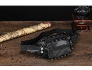 Detailed view of black PU leather waist bag with multiple layers on a vintage desk