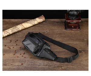 Top-down view of black PU leather fanny pack with zippers on a rustic wooden table
