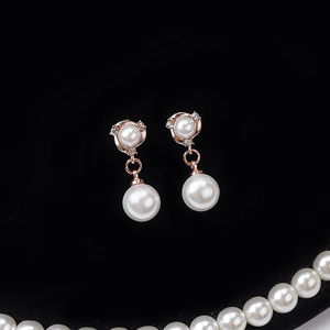 Elegant rose gold pearl drop earrings with sparkling diamonds on a black velvet background