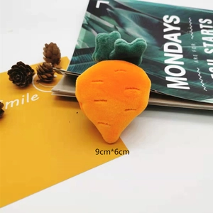 Close-up of a plush carrot pin in orange and green on a magazine with decorative accessories
