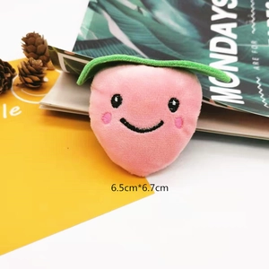 Detail view of 6.5cm plush peach brooch with embroidered face and green leaf decoration