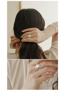 Close-up of minimalist layered silver ring and T-bar chain bracelet on female model