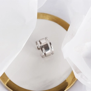 Macro detail of silver S925 triple-layer open band ring on an elegant white tray