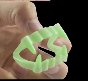Close-up of glow-in-the-dark green vampire teeth prop for Halloween costumes