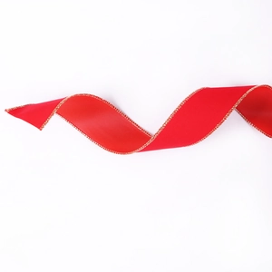 Close-up of red velvet Christmas ribbon with gold wired edges on white background