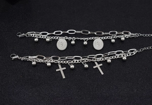 Detail of silver double-layered bracelets featuring crosses and religious oval charms