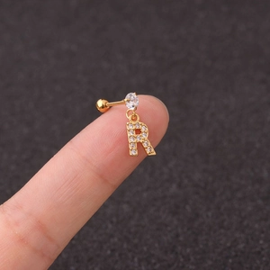 Detail of gold letter R cartilage earring with clear zircon crystals on model ear
