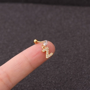 Macro shot of gold letter Z cartilage earring with sparkling zircons on fingertip