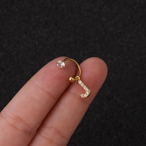 Vue macro d'un piercing en acier inoxydable doré lettre J avec zircone cubique sur le doigt