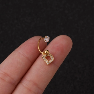 Gros plan d'un clou d'oreille en forme de lettre D dorée avec zircon cubique