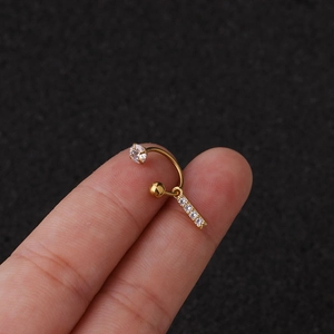 Détail macro du piercing en C en acier doré avec pendentif lettre en zircone