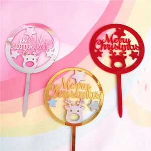 Macro shot of three Merry Christmas acrylic cake toppers in gold, silver, and red finish