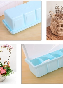 Detail of light blue 3-compartment kitchen spice box with lid and spoon on wood table