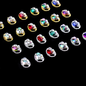 Assorted oval crystal nail charms with rhinestones and pearls on black background