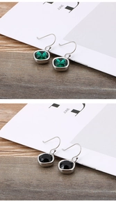 Detail view of square zircon earrings in green and black colors on display cards