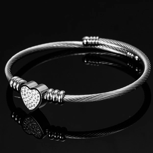 Detailed macro of silver cable wire cuff bracelet featuring a sparkling diamond heart charm