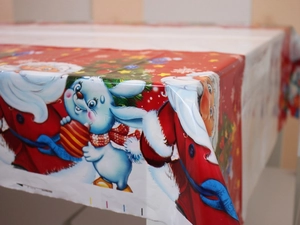 Détail d'une nappe de Noël en plastique avec des motifs du Père Noël et de petits lapins