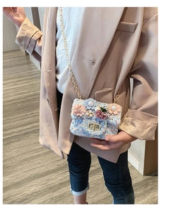 Dettaglio mini borsa a tracolla in tweed con fiori 3D e perla su tessuto azzurro
