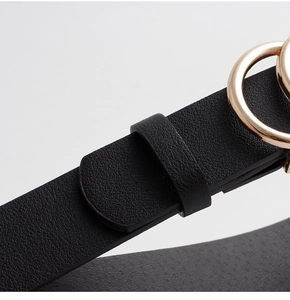 Close-up of black leather belt featuring a polished gold round buckle and textured finish