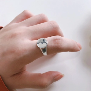 Close-up of minimalist 925 silver signet ring with engraved abstract pattern on a hand