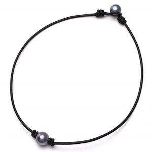 Detail of black leather cord choker featuring two large dark grey pearls tied at ends