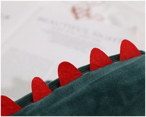 Macro detail of plush green dinosaur bag with soft texture and red serrated dorsal fin