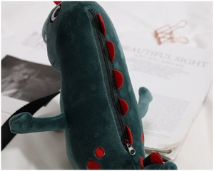 Detail of green plush dinosaur bag featuring red spine accents and a smooth metal zipper