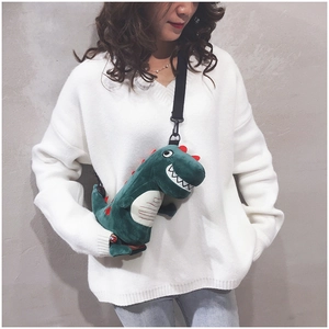 Detail of green plush dinosaur crossbody bag with adjustable strap worn by a model