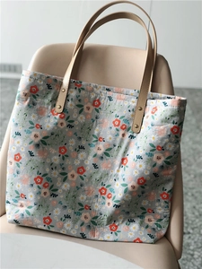 Close-up of a floral canvas tote bag with daisy patterns and premium leather handles