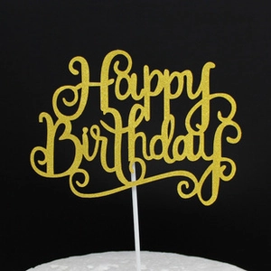 Macro shot of gold glitter Happy Birthday cake topper on a white cake with black background