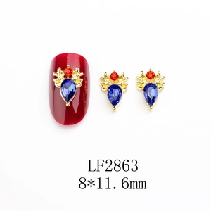 Détail de bijou d'ongle tête de cerf doré avec strass bleus et rouges scintillants