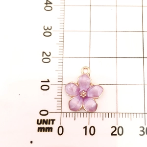 Macro view of purple enamel flower pendant on a grid mat showing 15mm size