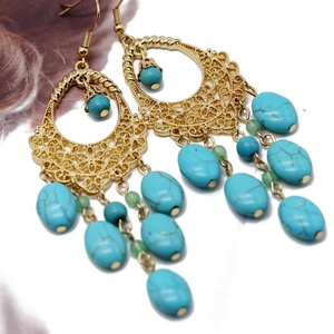 Detail of vintage gold hollow earrings with turquoise beads and intricate filigree patterns