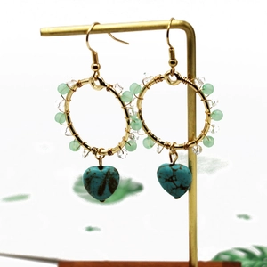Detailed close-up of heart-shaped turquoise drop earrings with gold wire and beads