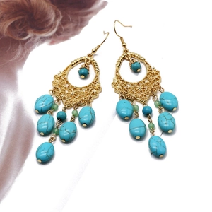 Detail of bohemian gold teardrop earrings with turquoise beads and tassel design