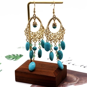 Detailed macro of bohemian hollow filigree earrings with turquoise bead accents