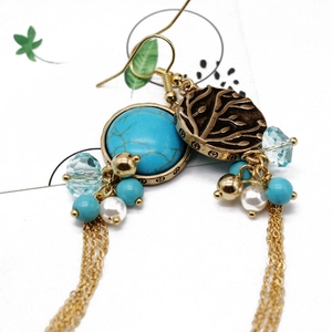 Macro detail of bohemian turquoise drop earrings with gold long chain tassels and pearls