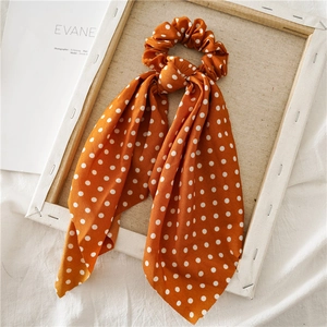 Detailed close-up of orange polka dot hair scrunchie with silk scarf on elegant decor
