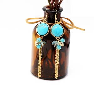 Detail of bohemian turquoise tassel earrings with blue beads and golden chain fringe