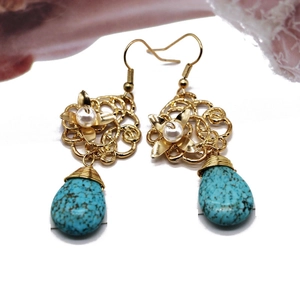Detail of bohemian gold earrings with turquoise teardrops and floral pearl accents