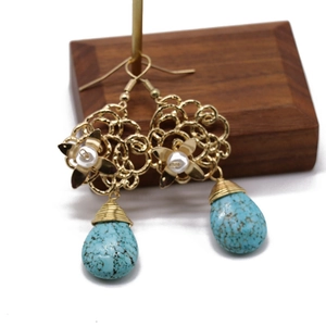 Macro detail of bohemian hollow flower earrings with turquoise teardrop and pearl