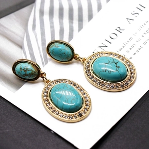 Macro detail of turquoise drop earrings with gold-plated metal and crystal accents