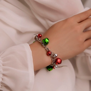Christmas bracelet featuring silver chain with red and green bells on female wrist