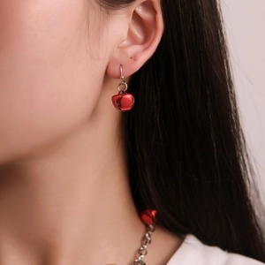 Close-up of model wearing festive red bell earrings and matching necklace set