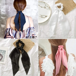 Close-up of elegant knotted satin hair scrunchies with long ribbons in four colors