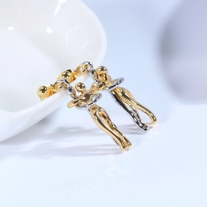Detailed view of dual-tone abstract hugging figures earrings on white ceramic