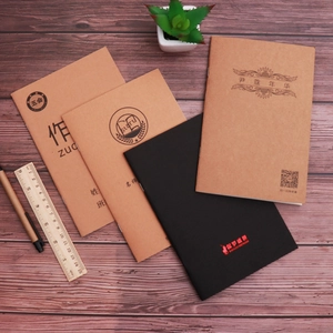 Close-up of minimalist kraft paper spiral notebooks on a dark wooden desk with stationery